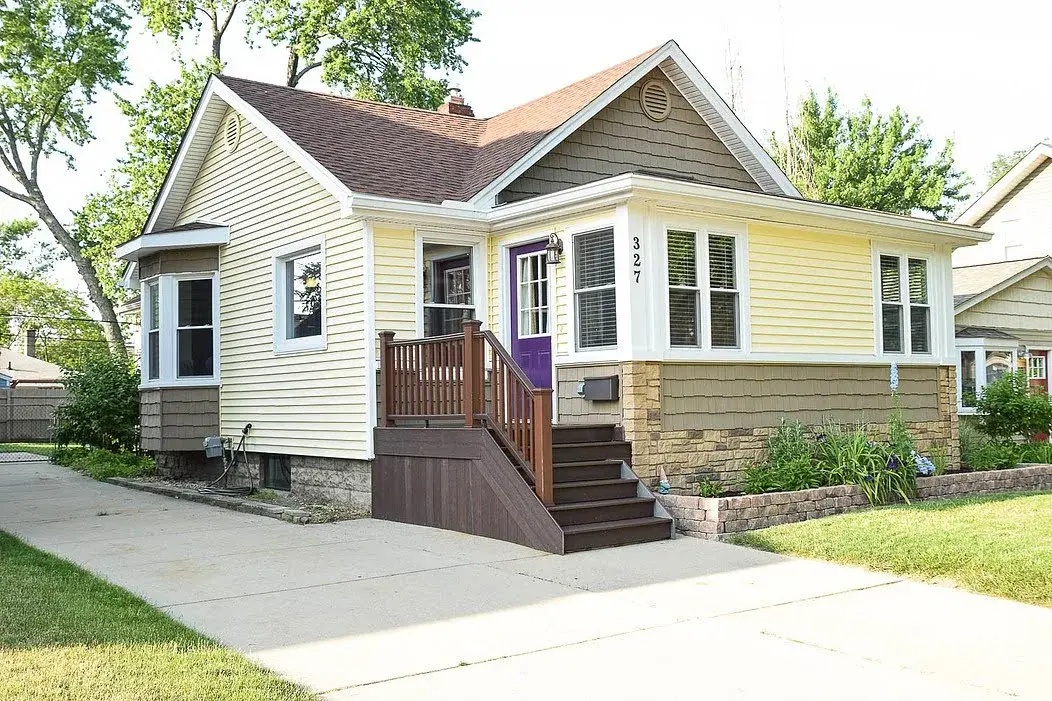 Driveway view of a small yellow home