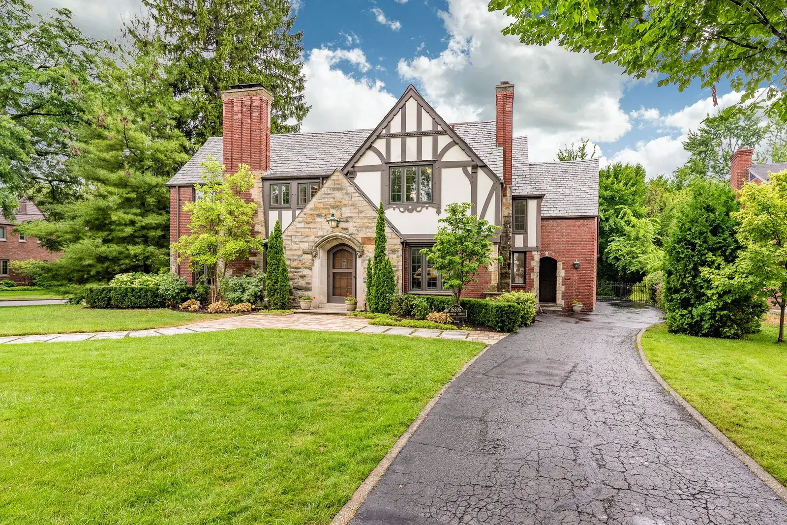 Tudor-style brick and stone home with front lawn and driveway